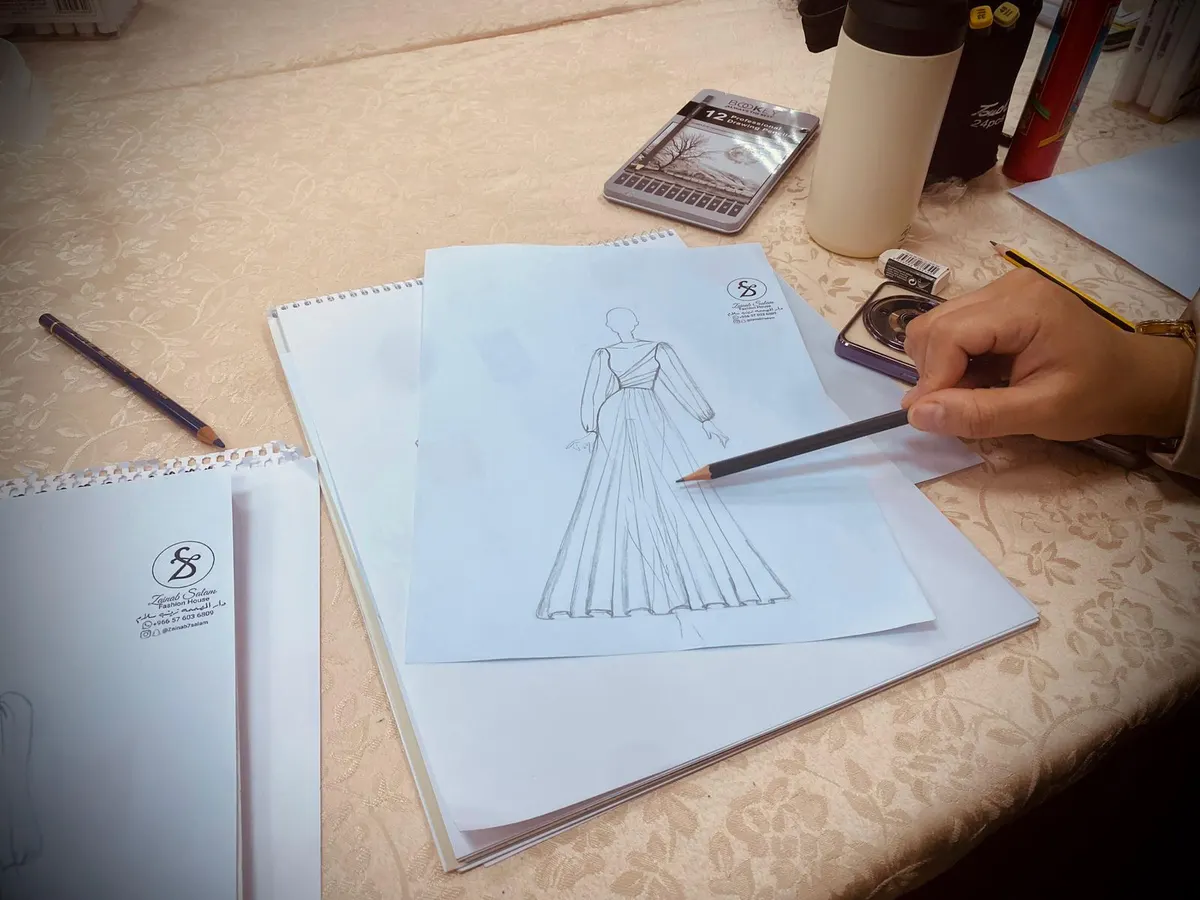 في ورشة لمستفيدات ضمان القطيف.. بـ قلم وورقة زينب آل ادخيل ترسم الخطوات الأولى لـ تصميم الأزياء